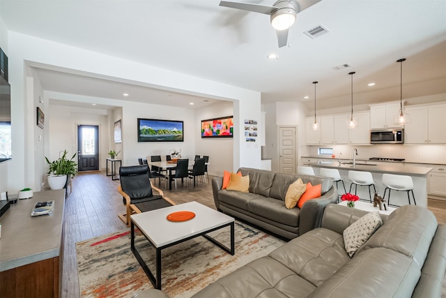 living room featuring ceiling fan, sink, and light hardwood / wood-style floors