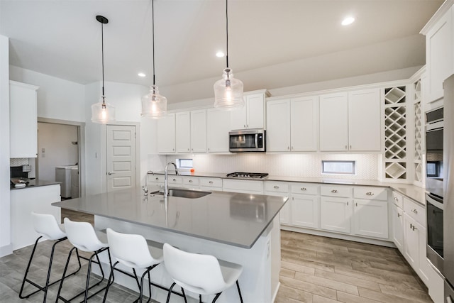 kitchen with hanging light fixtures, sink, white cabinets, and stainless steel appliances