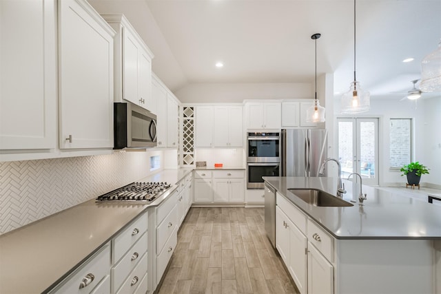 kitchen featuring sink, stainless steel appliances, pendant lighting, a center island with sink, and white cabinets