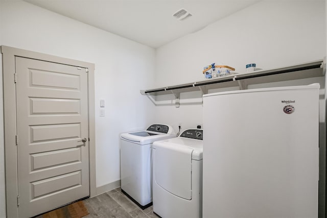 laundry room featuring separate washer and dryer and light hardwood / wood-style floors