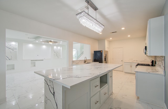 kitchen with tasteful backsplash, decorative light fixtures, a kitchen island, light stone counters, and stainless steel fridge with ice dispenser