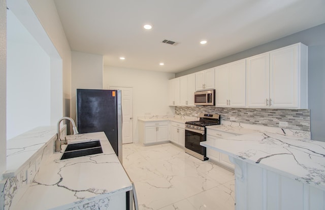 kitchen with white cabinets, sink, tasteful backsplash, light stone counters, and stainless steel appliances