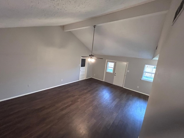 unfurnished living room with lofted ceiling with beams, ceiling fan, dark wood-type flooring, and a textured ceiling