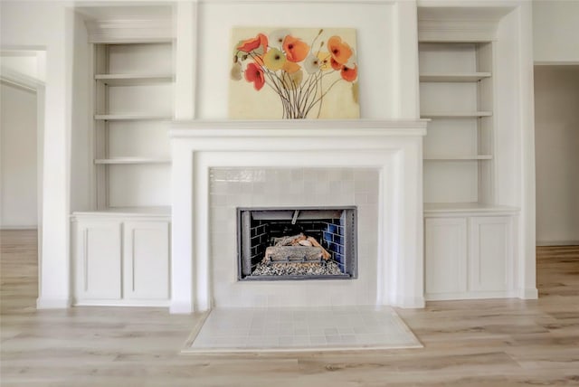 details featuring built in shelves, a fireplace, and hardwood / wood-style floors