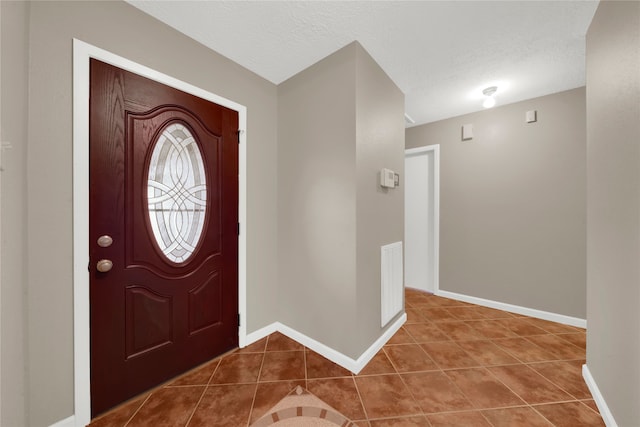 tiled foyer entrance with a textured ceiling