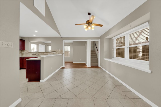 kitchen with sink, vaulted ceiling, ceiling fan, light tile patterned flooring, and kitchen peninsula