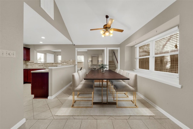 tiled dining room featuring ceiling fan, sink, and vaulted ceiling