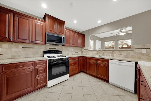 kitchen featuring ceiling fan, sink, light stone counters, white appliances, and decorative backsplash