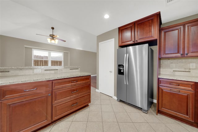 kitchen featuring ceiling fan, light tile patterned floors, tasteful backsplash, light stone counters, and stainless steel fridge with ice dispenser