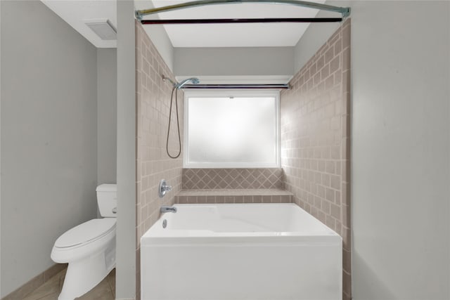 bathroom with bathing tub / shower combination, tile patterned flooring, and toilet