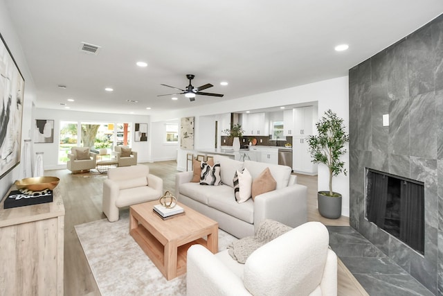 living room with ceiling fan, a fireplace, and light hardwood / wood-style floors