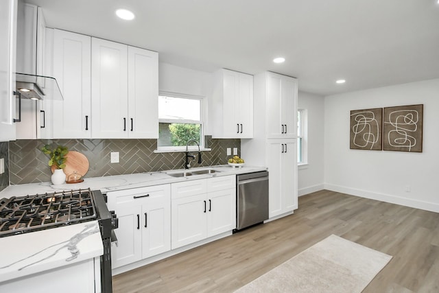 kitchen with light stone counters, white cabinetry, stainless steel dishwasher, and sink