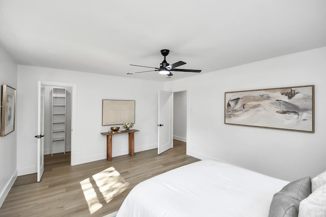 bedroom featuring a closet, light hardwood / wood-style floors, a spacious closet, and ceiling fan