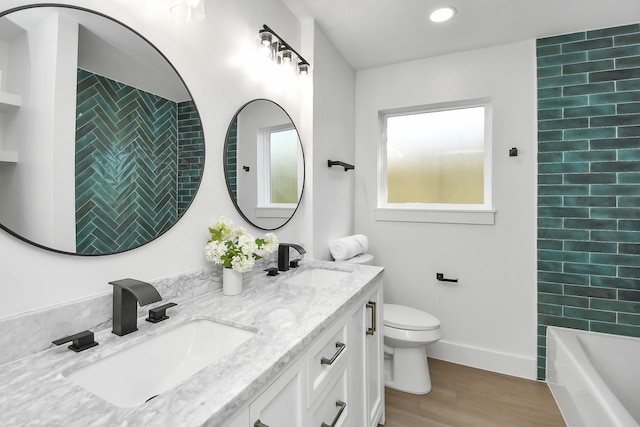 full bathroom featuring vanity, wood-type flooring, tiled shower / bath combo, and toilet