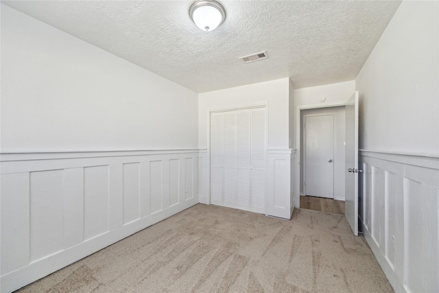 carpeted spare room featuring a textured ceiling