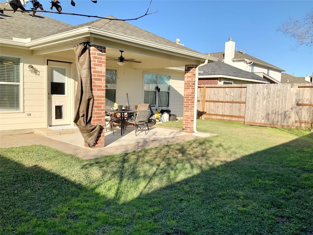 rear view of house with ceiling fan, a yard, and a patio