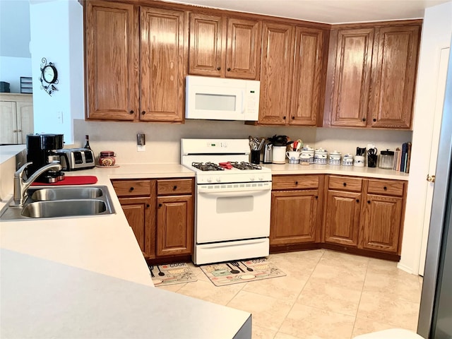 kitchen featuring white appliances, sink, and light tile patterned floors