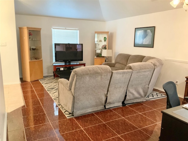 living room with dark tile patterned flooring and vaulted ceiling