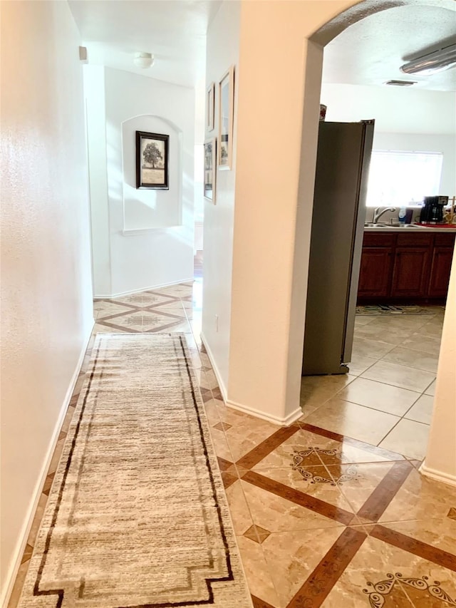 hall featuring sink and light tile patterned floors