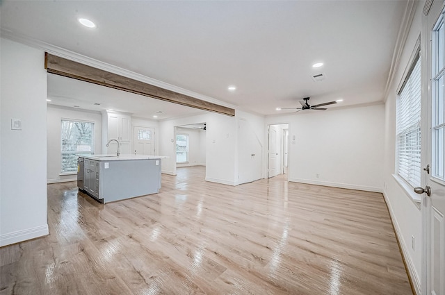 unfurnished living room with light hardwood / wood-style flooring, ceiling fan, crown molding, and sink