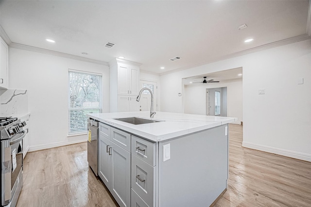 kitchen with light stone countertops, sink, ceiling fan, stainless steel appliances, and a kitchen island with sink