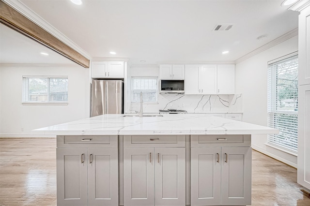 kitchen with light stone countertops, stainless steel fridge, and a kitchen island