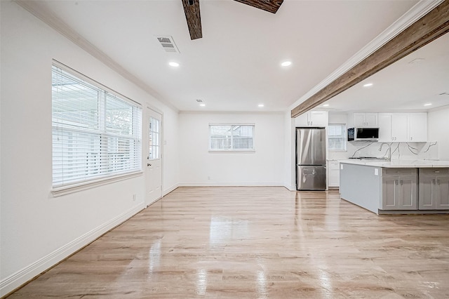 kitchen featuring stainless steel fridge, tasteful backsplash, ornamental molding, sink, and white cabinetry