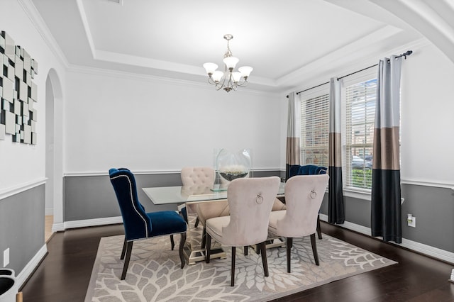 dining area with baseboards, arched walkways, wood finished floors, an inviting chandelier, and a tray ceiling