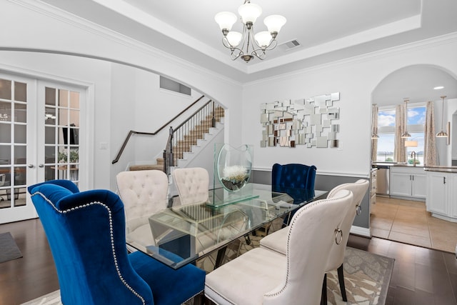 dining room with french doors, a raised ceiling, a chandelier, and crown molding