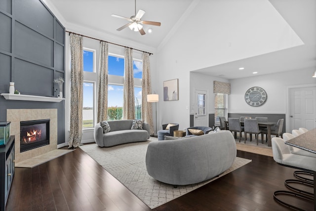 living room featuring dark wood-type flooring, ornamental molding, high vaulted ceiling, a fireplace, and ceiling fan