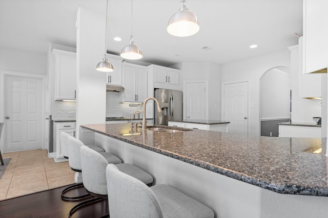 kitchen with white cabinets, a kitchen island, stainless steel refrigerator with ice dispenser, and backsplash