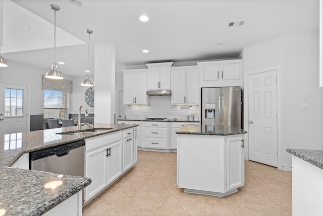 kitchen with appliances with stainless steel finishes, white cabinets, sink, and a center island with sink