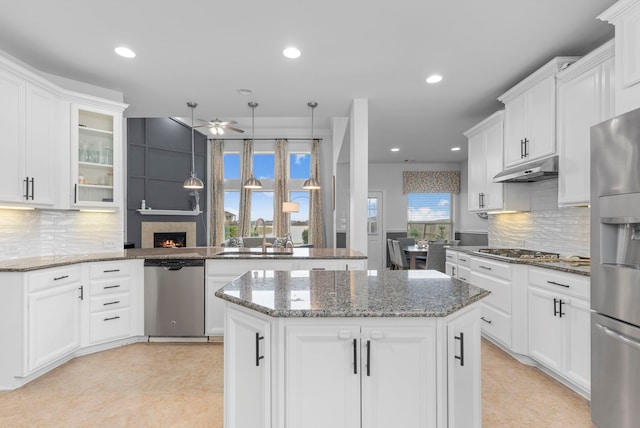 kitchen with sink, a center island, ceiling fan, a large fireplace, and appliances with stainless steel finishes