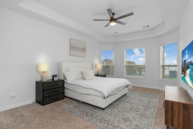 carpeted bedroom featuring baseboards, visible vents, and a raised ceiling