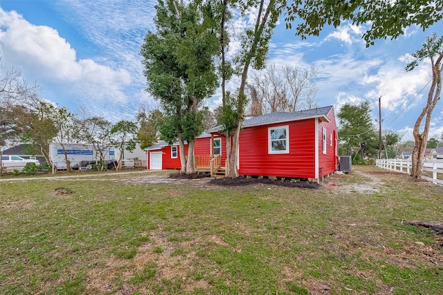 exterior space featuring central AC, a yard, a garage, and an outdoor structure