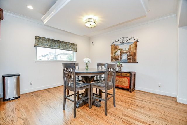 dining space with ornamental molding and light hardwood / wood-style flooring