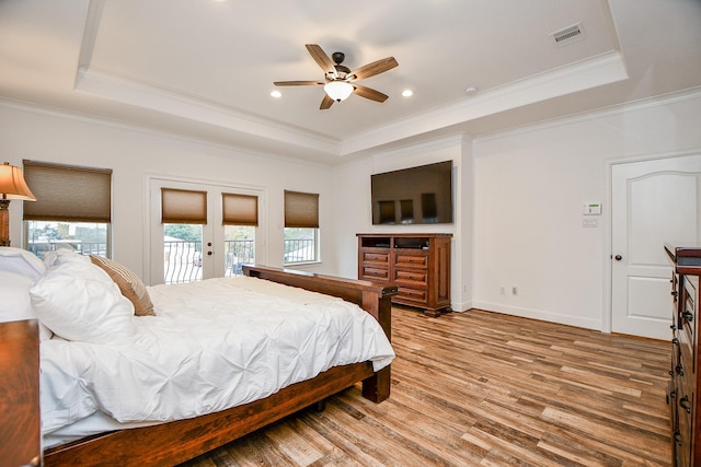 bedroom featuring ceiling fan, access to exterior, a tray ceiling, ornamental molding, and french doors