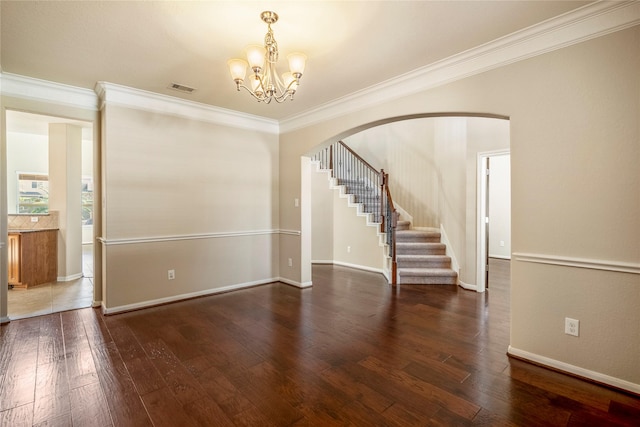 empty room featuring dark wood-type flooring, an inviting chandelier, and crown molding