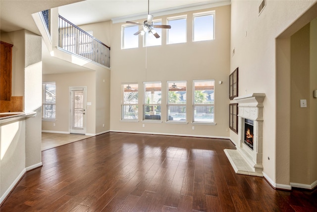 unfurnished living room with a towering ceiling, ceiling fan, and dark hardwood / wood-style flooring