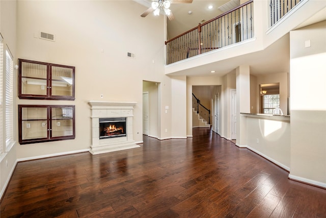 unfurnished living room featuring a towering ceiling, dark hardwood / wood-style flooring, ceiling fan, and sink