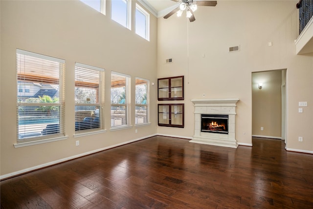 unfurnished living room with a high ceiling, a fireplace, ceiling fan, and wood-type flooring