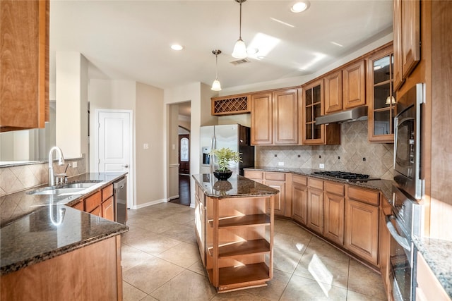 kitchen featuring sink, decorative backsplash, dark stone counters, hanging light fixtures, and appliances with stainless steel finishes