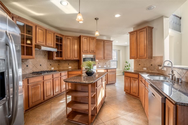 kitchen featuring pendant lighting, a center island, dark stone counters, appliances with stainless steel finishes, and sink