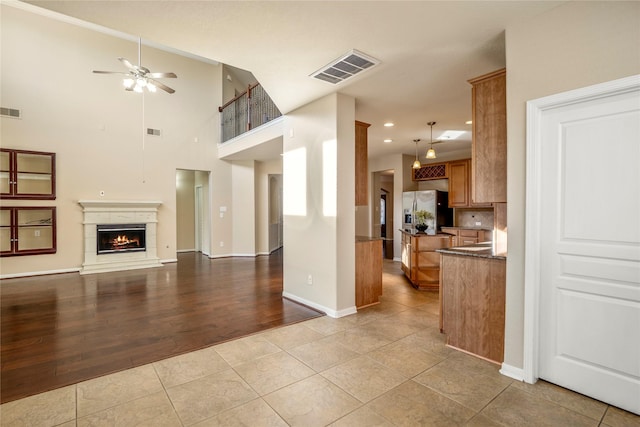 kitchen with light tile patterned floors, ceiling fan, pendant lighting, stainless steel fridge, and backsplash