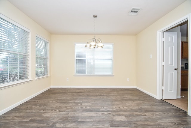 unfurnished dining area with a chandelier and dark hardwood / wood-style flooring