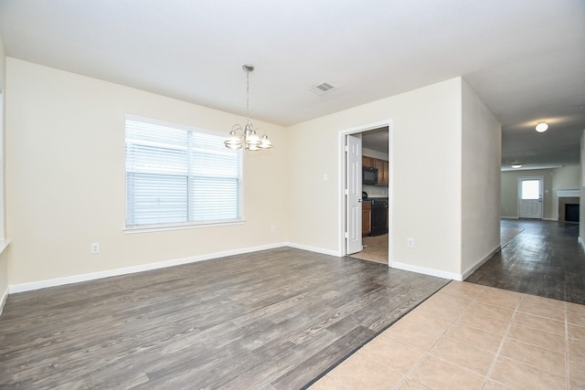 empty room with light wood-type flooring and an inviting chandelier