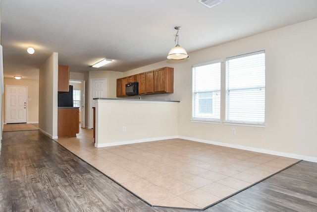 kitchen with black appliances, pendant lighting, and light hardwood / wood-style floors