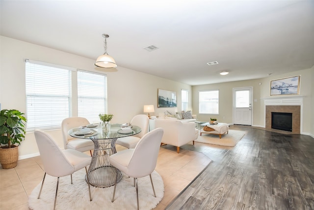 dining space featuring a tile fireplace and light hardwood / wood-style flooring