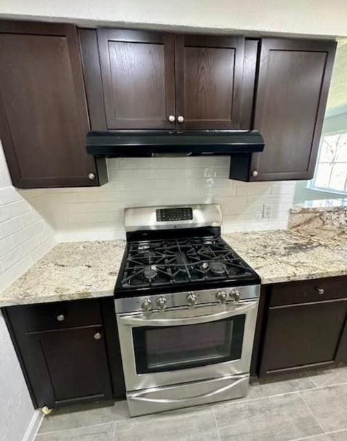 kitchen featuring light stone countertops, dark brown cabinets, and stainless steel gas range