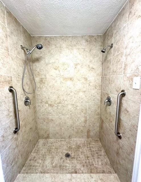 bathroom with a textured ceiling and tiled shower